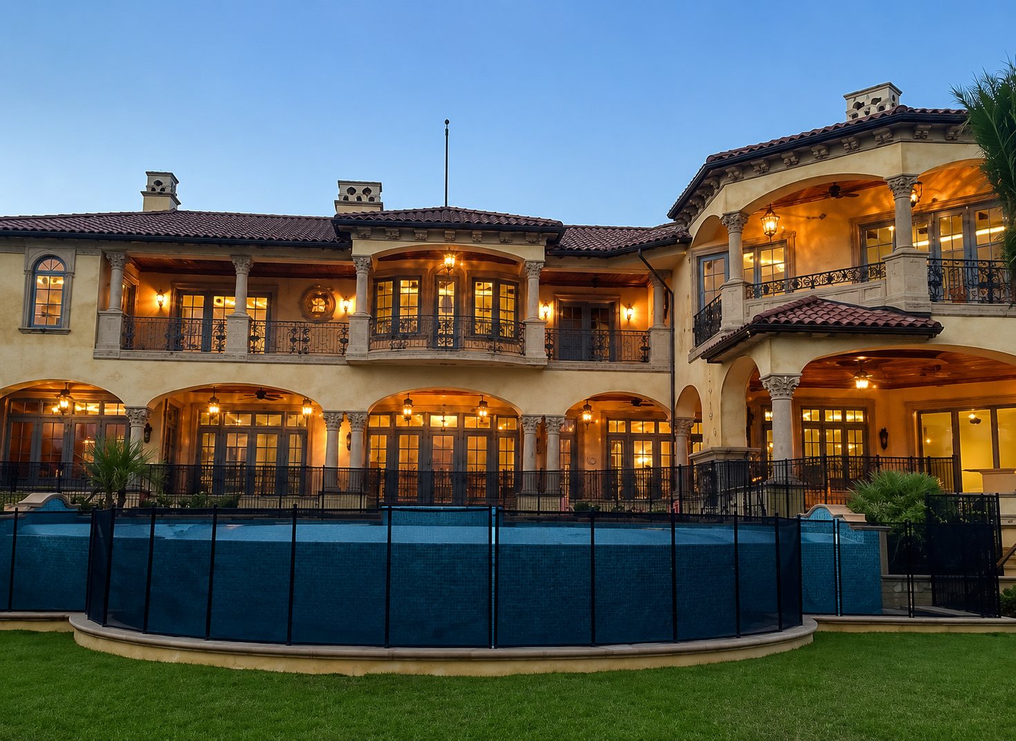 Luxury Mediterranean home at dusk with warm glowing windows