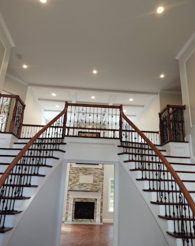 Grand curved double staircase with warm recessed lighting