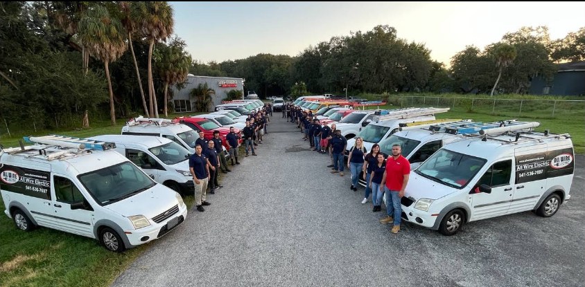 The All Wire Electric team standing proudly in front of their service fleet